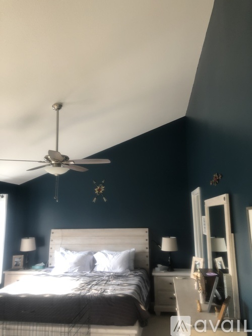 A bedroom with a bed, dresser, mirror, and ceiling fan.