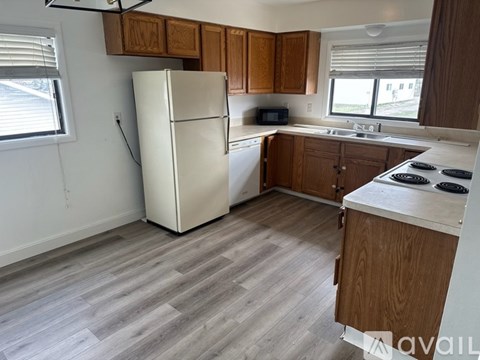 A kitchen with a white refrigerator, wooden cabinets, and a stove top oven.