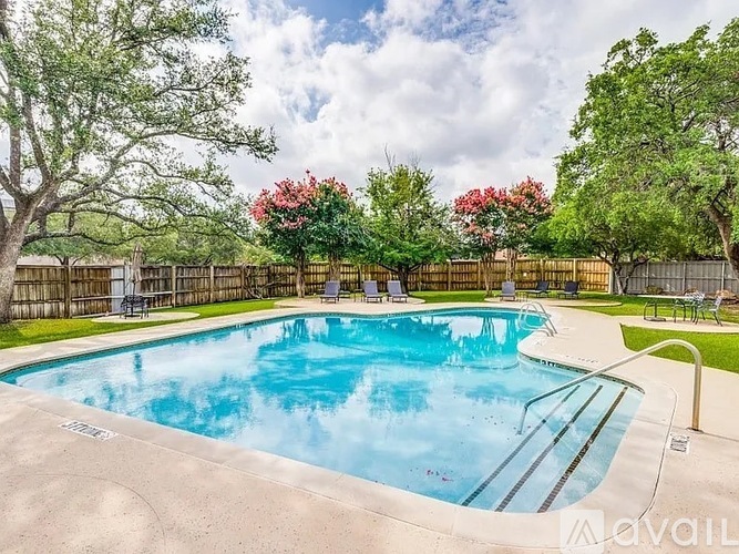 A pool surrounded by a wooden fence and trees.