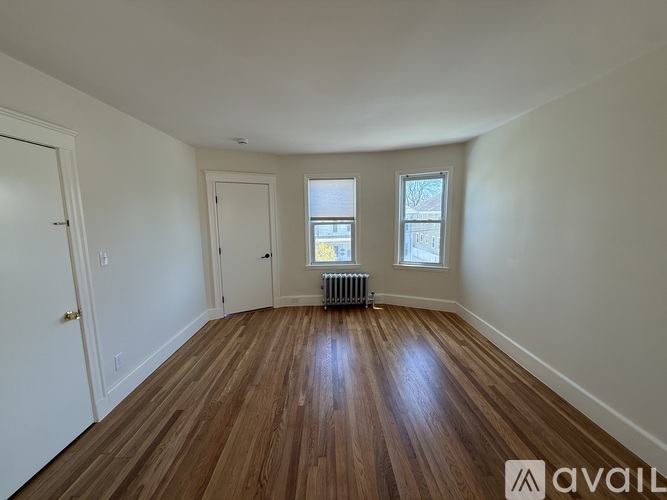 A room with wooden floors and two windows.