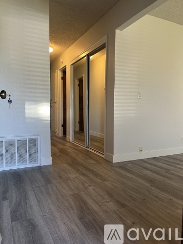 A room with a wooden floor and a wall with a window and a door.