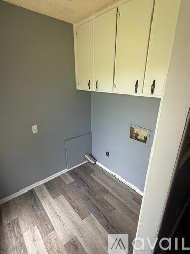 A room with wooden flooring and white cabinets.