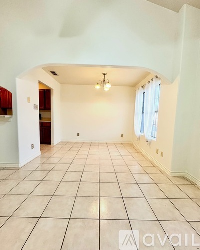 A spacious room with white walls and a tiled floor.