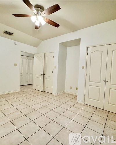A room with a ceiling fan and tile flooring.