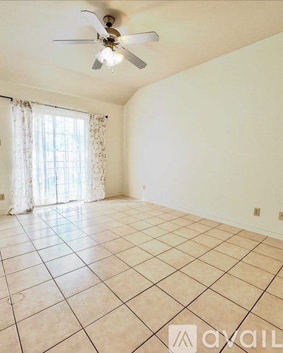 A room with a ceiling fan and tiled flooring.