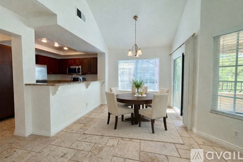 A dining room with a table set for four and a kitchen area in the background.