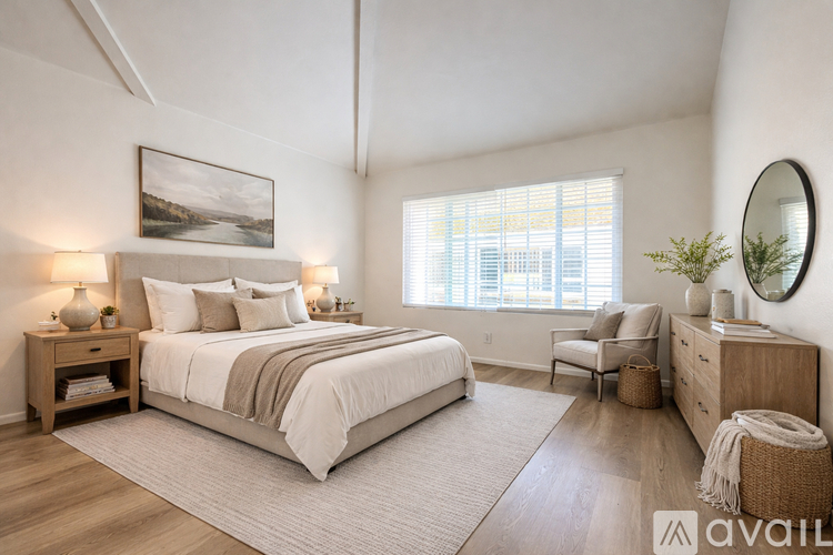 A well-lit bedroom with a large bed and a painting on the wall.