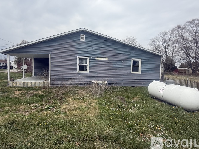 A blue house with a white tank in front of it.