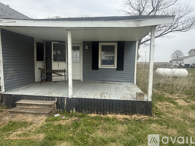A porch of a house with a white door and a window.