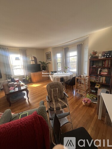 A living room with a couch, chairs, and a bookshelf.