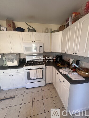 A kitchen with white cabinets and a stove top oven.