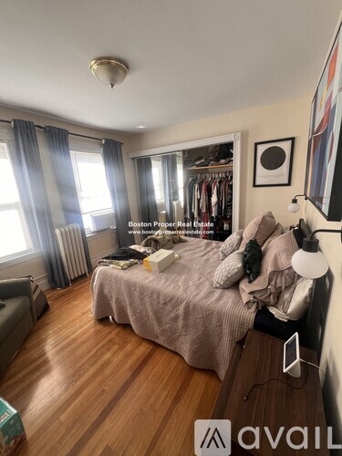 A bedroom with a bed, a couch, and a window with curtains.