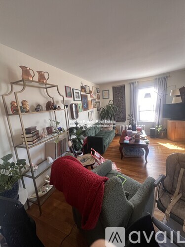 A person is sitting on a couch in a living room with a shelf of pottery on the wall.