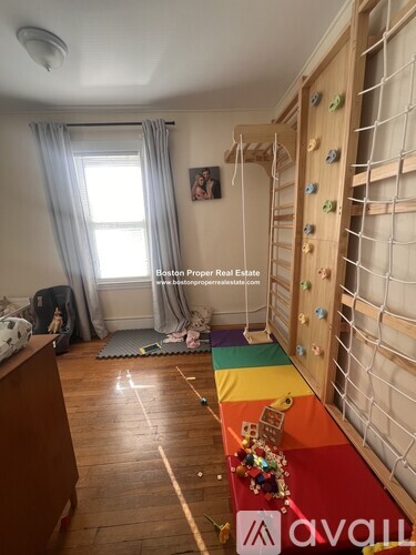A room with a wooden floor and a rainbow-colored mattress.