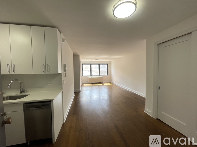 A kitchen with white cabinets and a wooden floor.