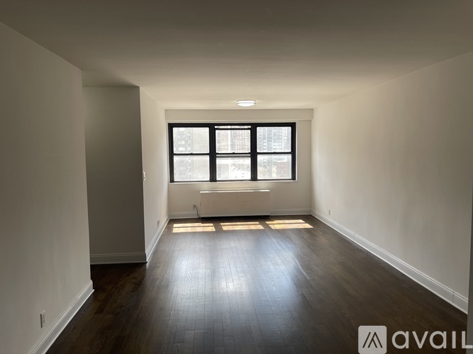 A room with wooden floors and a window with blinds.
