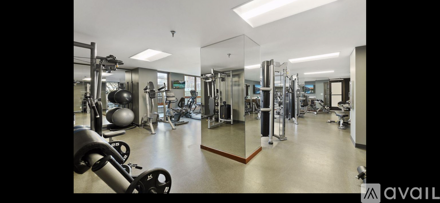 A gym with a mirrored wall and various exercise equipment.