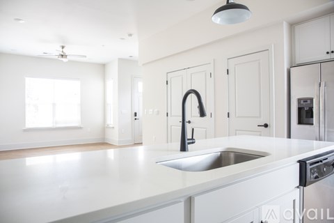 A modern kitchen with white cabinets and a stainless steel sink.