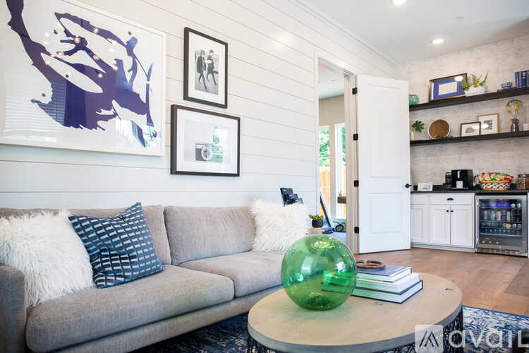 A living room with a grey couch and a green glass ball on the coffee table.