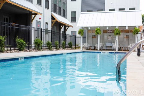 A pool in front of a white building with a black fence.