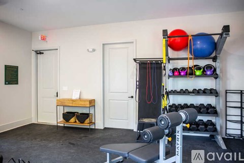 A gym room with a bench, weights, and exercise balls.