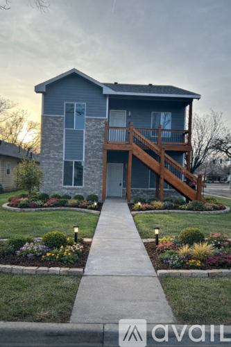 A two-story house with a balcony and a front yard with flowers.