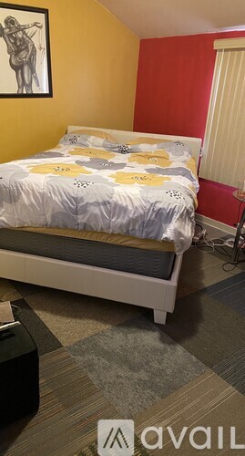 A bedroom with a bed, pillows, and a carpet.