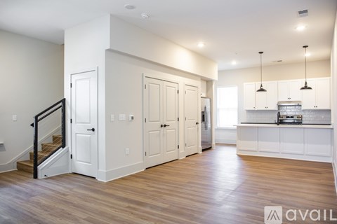 A spacious kitchen with white cabinets and a wooden floor.