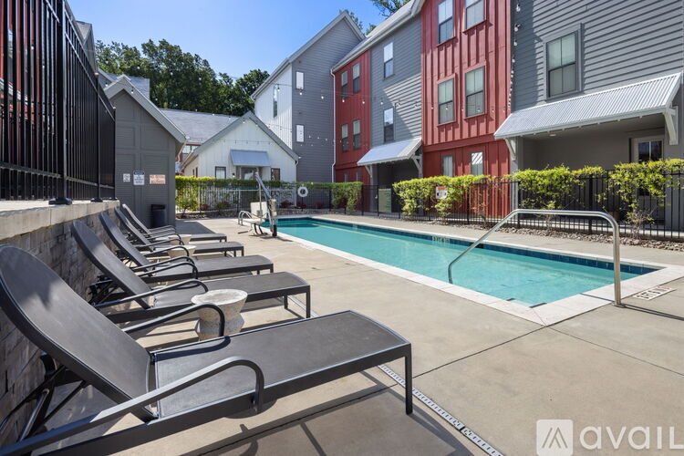 A pool surrounded by lounge chairs and buildings in the background.
