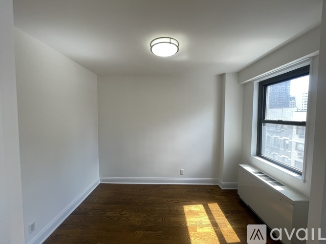 A well-lit, empty room with a window on the right side.