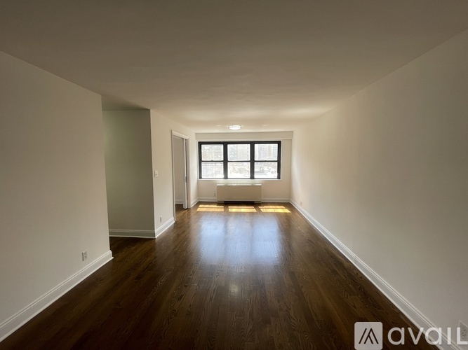 A spacious room with wooden floors and a window.