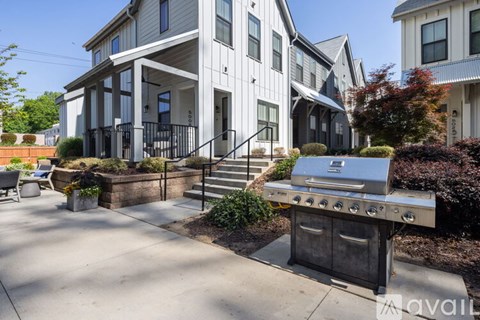 A modern house with a BBQ grill in the front yard.