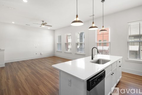 A kitchen with a white countertop and wooden flooring.