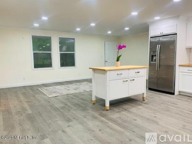 A kitchen with a white island and a refrigerator.