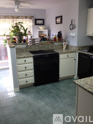 A kitchen with a black dishwasher and white cabinets.