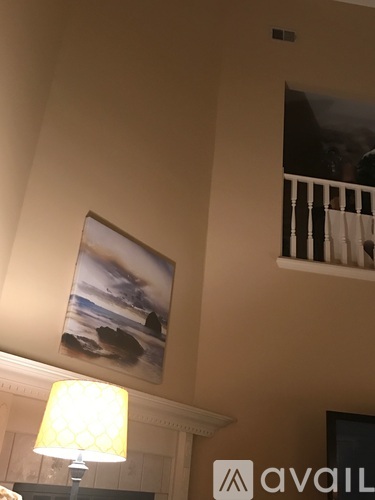 A painting of a beach scene hangs on a wall above a lamp.