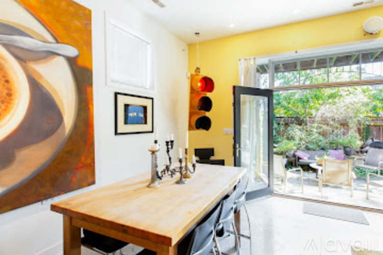 A wooden table with four chairs and a painting of a cup of coffee on the wall.
