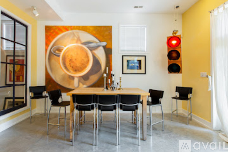 A dining room with a large painting of a bowl of soup on the wall.