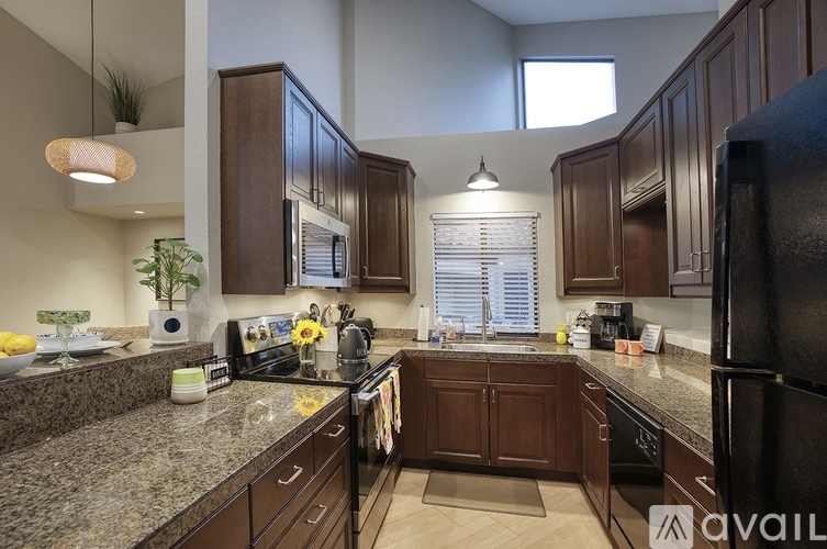 A kitchen with dark brown cabinets and granite countertops.