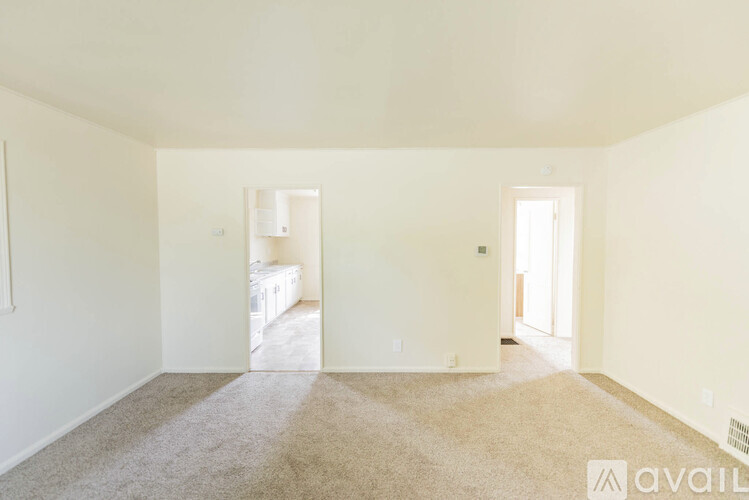 A carpeted room with a window and a door leading to another room.