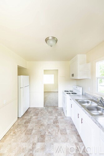 A kitchen with white cabinets and a tiled floor.