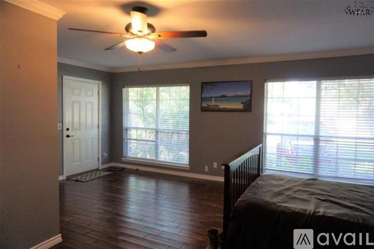 A bedroom with a bed, a ceiling fan, and a window with blinds.