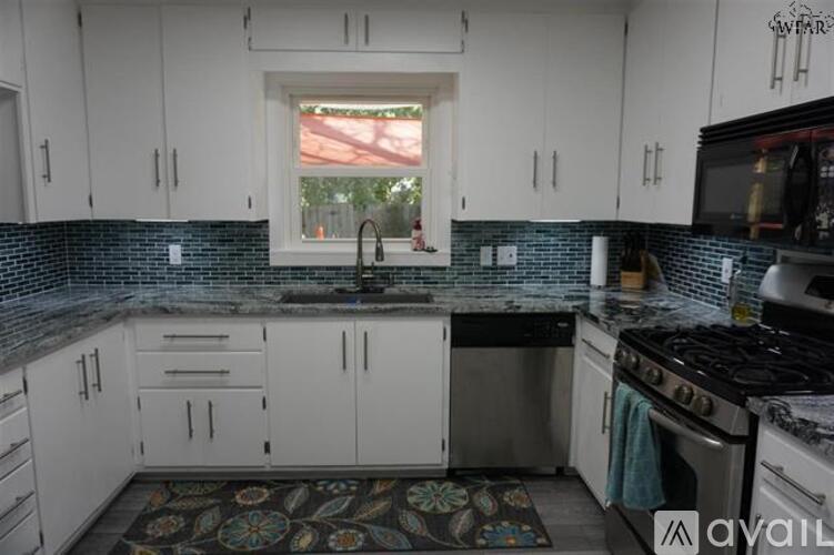 A kitchen with white cabinets and a black countertop.