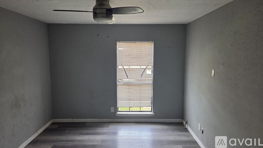 A room with a ceiling fan and a window with blinds.