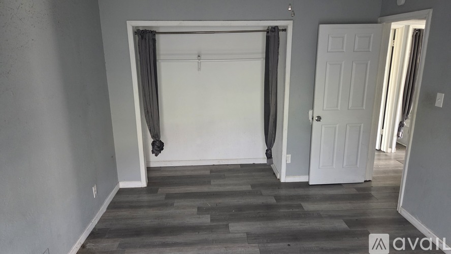 A room with a white door and a wooden floor.