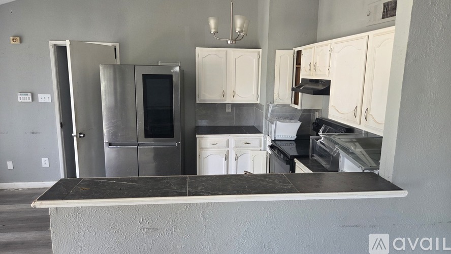 A kitchen with a black countertop and white cabinets.