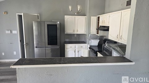 A kitchen with a black countertop and white cabinets.