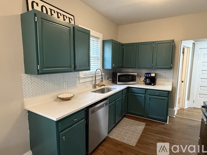 A kitchen with green cabinets and a coffee sign on the wall.
