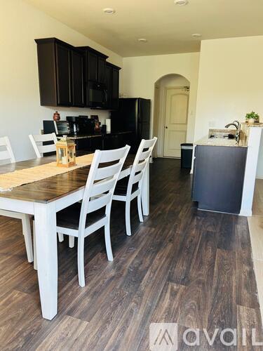 A kitchen with a table and chairs in the foreground and a refrigerator in the background.