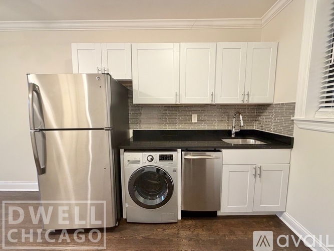 A kitchen with a stainless steel refrigerator and a washer and dryer combo unit.